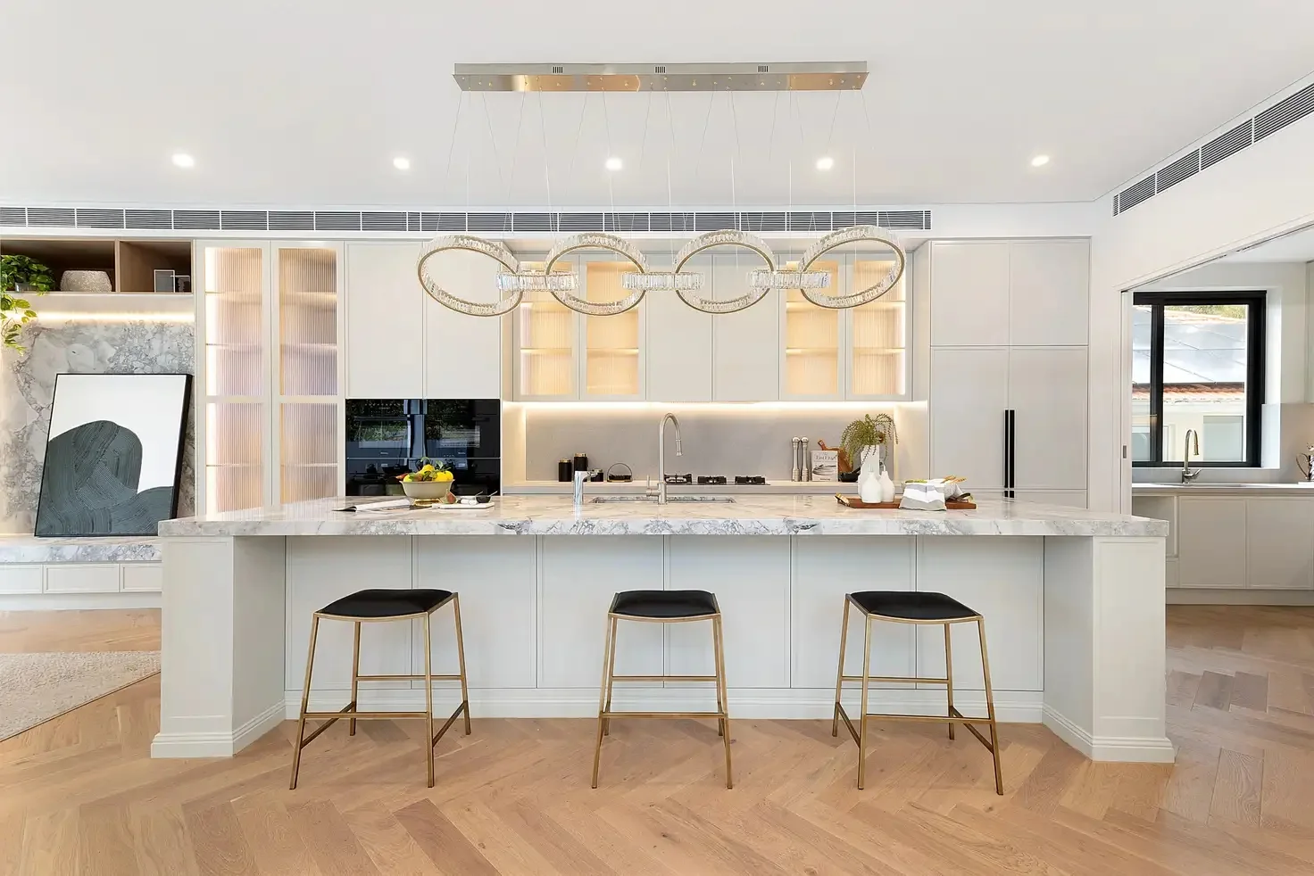 Cream kitchen cabinetry, illuminated display cupboards and a stone island